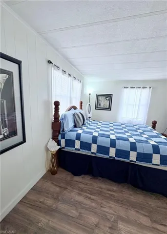 Bedroom with dark wood-style flooring and wood walls
