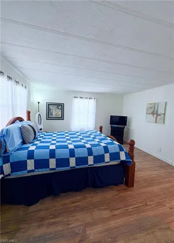 Bedroom featuring dark wood-type flooring, multiple windows, and wooden walls