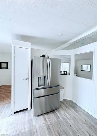Kitchen featuring stainless steel refrigerator with ice dispenser, light wood-style flooring, and a textured ceiling