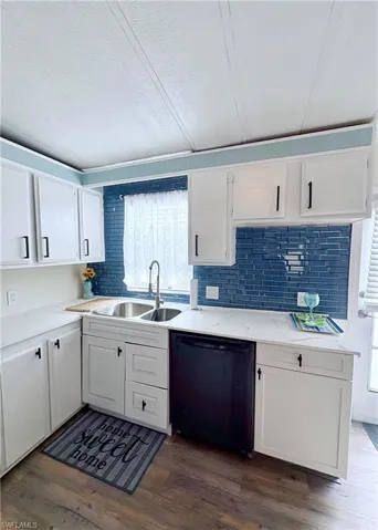 Kitchen with white cabinetry, black dishwasher, a textured ceiling, dark wood finished floors, and tasteful backsplash