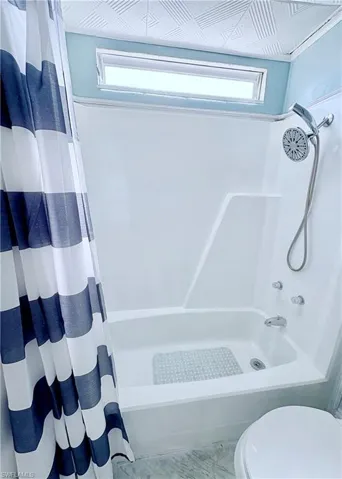 Bathroom with healthy amount of natural light and shower / bath combo with shower curtain