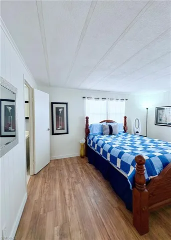 Bedroom featuring wooden walls, wood finished floors, and a textured ceiling