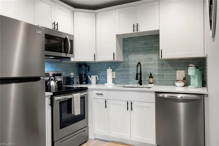 Kitchen featuring appliances with stainless steel finishes, white cabinets, and decorative backsplash