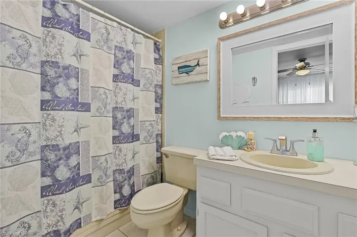 Bathroom featuring curtained shower, vanity, tile patterned floors, and a ceiling fan