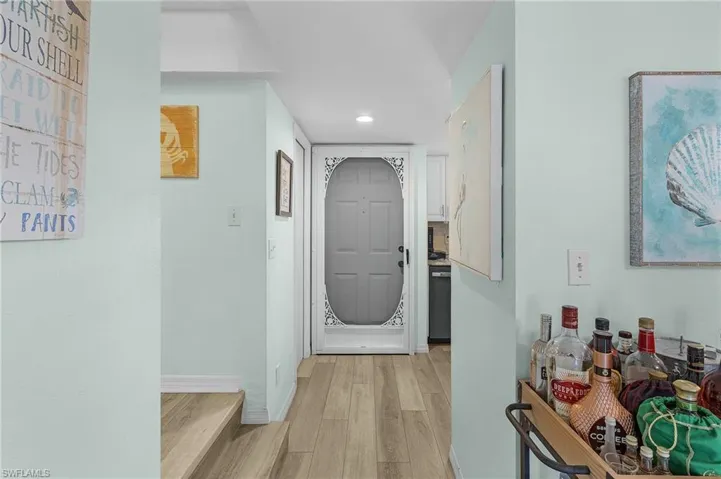 Hall with light wood finished floors and recessed lighting