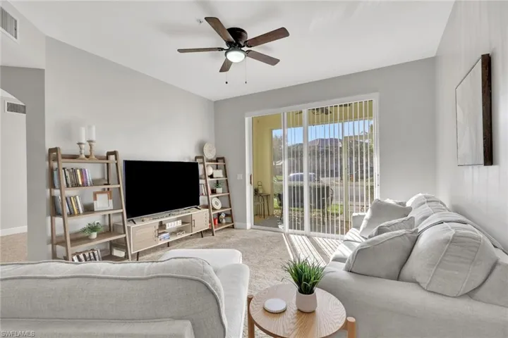 Carpeted living area with a ceiling fan and arched walkways