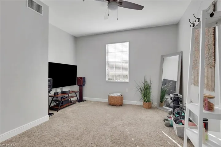 Carpeted den/office area with ceiling fan