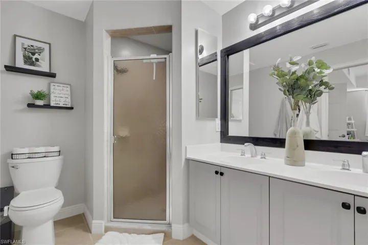 Bathroom featuring a shower stall, double vanity, and light tile patterned floors