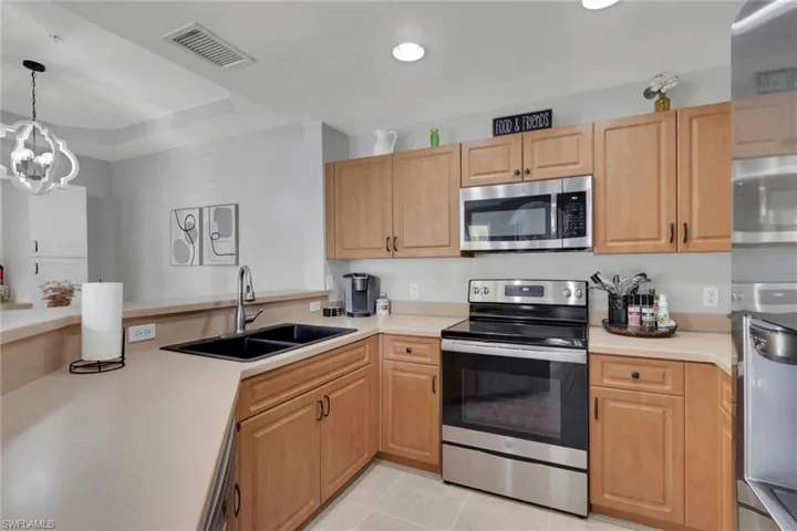 Kitchen featuring stainless steel appliances, light countertops, light tile patterned floors, and a peninsula