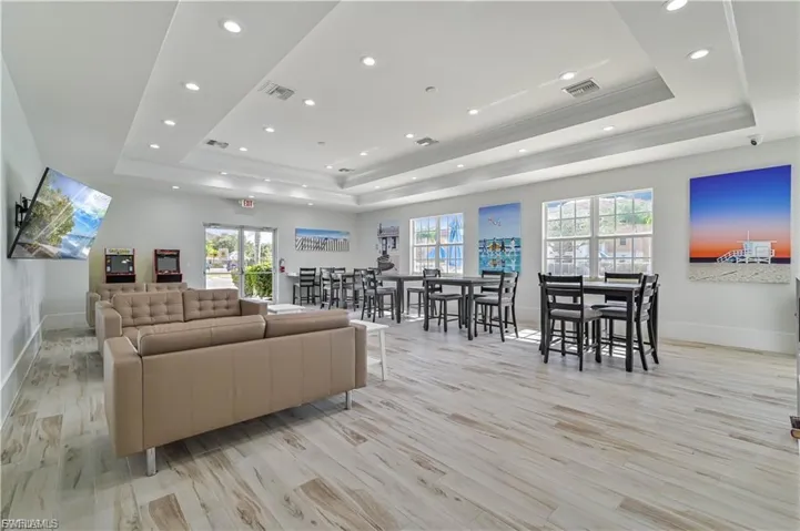 Living area featuring light wood-style flooring, recessed lighting, and a raised ceiling