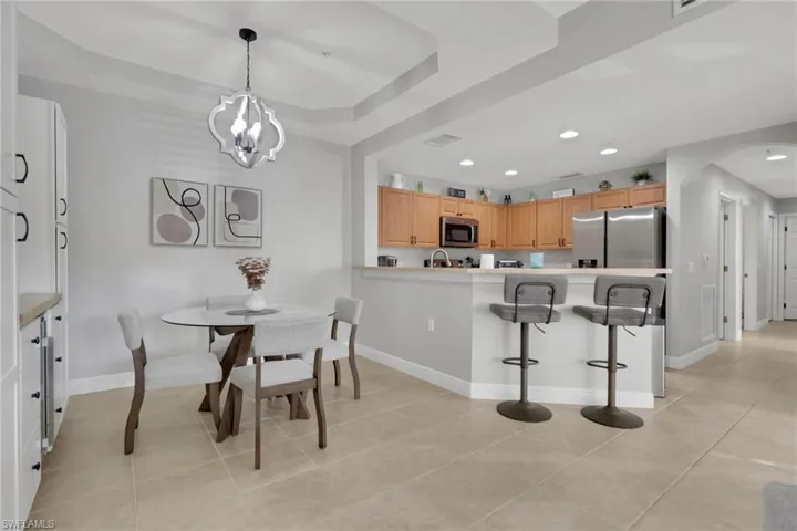 Dining area featuring arched walkways, recessed lighting, and light tile patterned floors