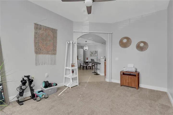 Carpeted den/office area with ceiling fan
