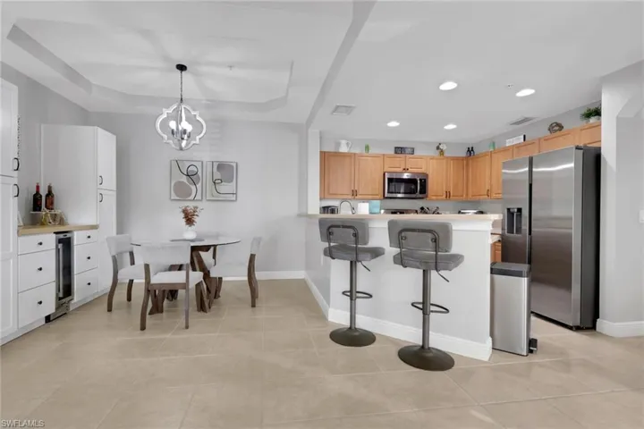 Kitchen with a breakfast bar area, stainless steel appliances, a peninsula, a tray ceiling, and light countertops