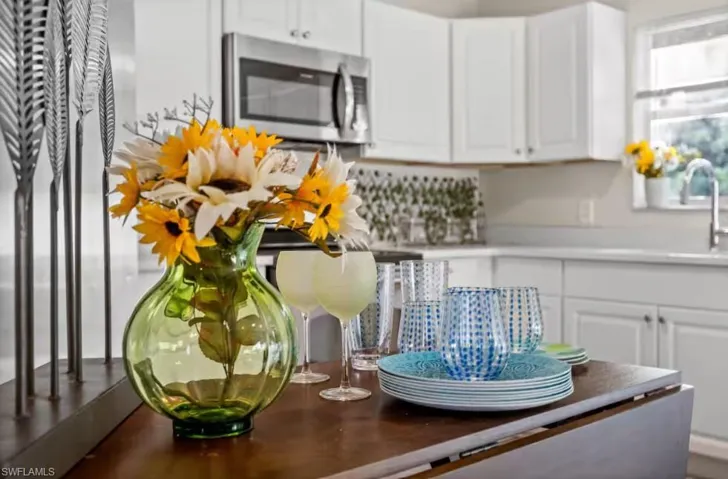 Kitchen featuring stainless steel microwave, white cabinets, and light countertops