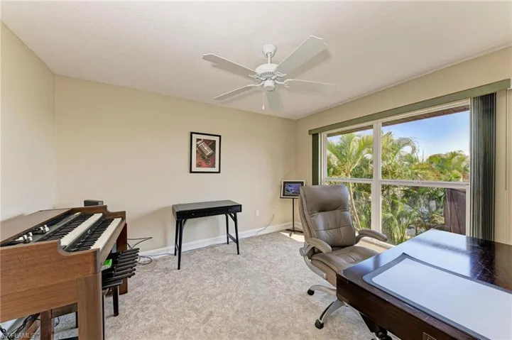 Office space with light carpet, ceiling fan, and a textured ceiling
