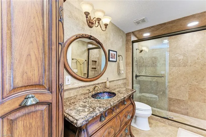 Bathroom with vanity, tile patterned flooring, toilet, a textured ceiling, and walk in shower