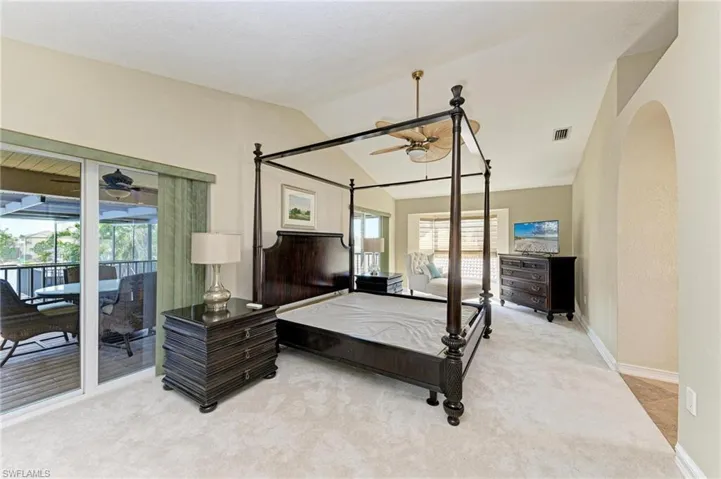 Carpeted bedroom with access to exterior, vaulted ceiling, and ceiling fan