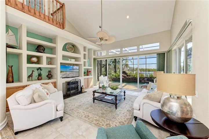 Living room with ceiling fan, built in features, and high vaulted ceiling