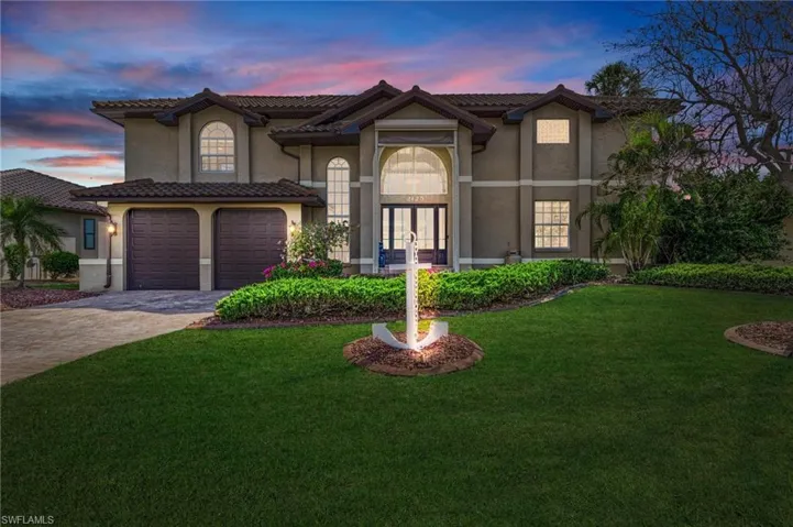 Mediterranean / spanish house with french doors, a garage, and a lawn