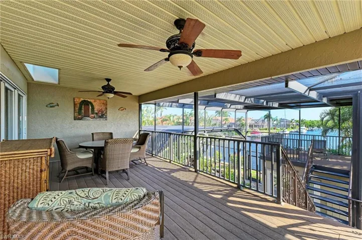 Wooden terrace featuring ceiling fan and a water view