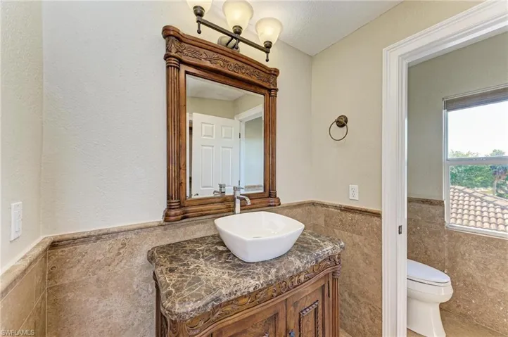 Bathroom with vanity, a textured ceiling, toilet, and tile walls