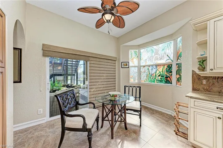 Dining space with ceiling fan, light tile patterned flooring, and a healthy amount of sunlight