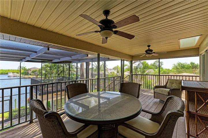 Sunroom / solarium with ceiling fan and a water view