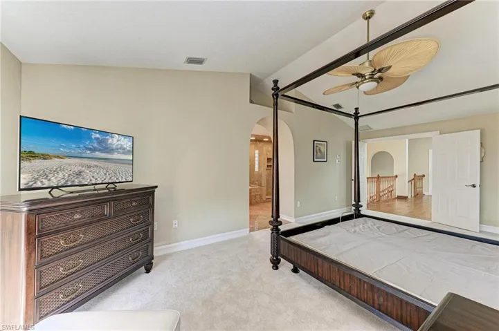 Bedroom featuring ceiling fan, light carpet, and vaulted ceiling