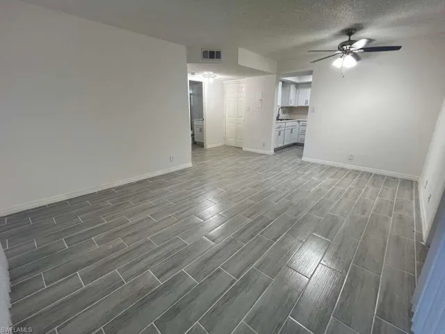 Unfurnished living room featuring a textured ceiling, wood tiled floors, and a ceiling fan
