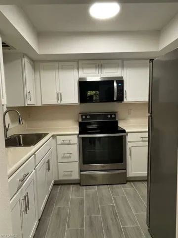 Kitchen with stainless steel appliances, white cabinets, and light countertops