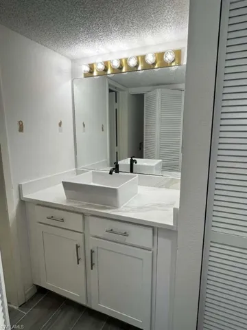 Bathroom featuring a closet, vanity, and a textured ceiling