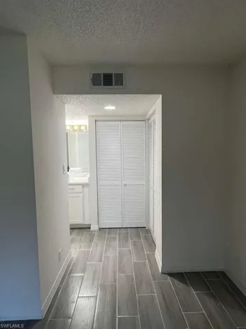 Unfurnished bedroom featuring a textured ceiling, wood finish floors, and a closet