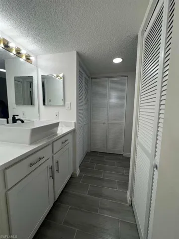 Bathroom featuring a closet, vanity, and a textured ceiling