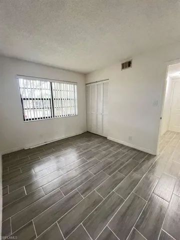 Unfurnished bedroom featuring a textured ceiling, a closet, and wood finish floors
