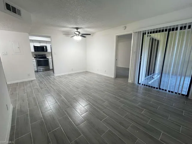 Unfurnished living room featuring wood tiled floors, a textured ceiling, and a ceiling fan