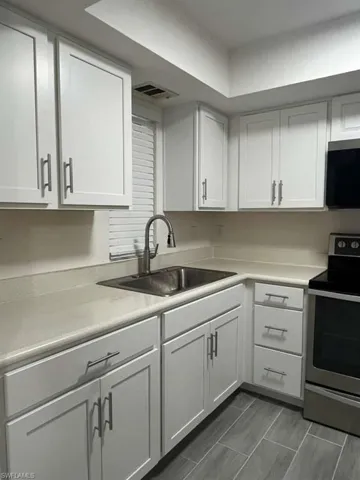 Kitchen featuring white cabinetry, stainless steel appliances, and light countertops