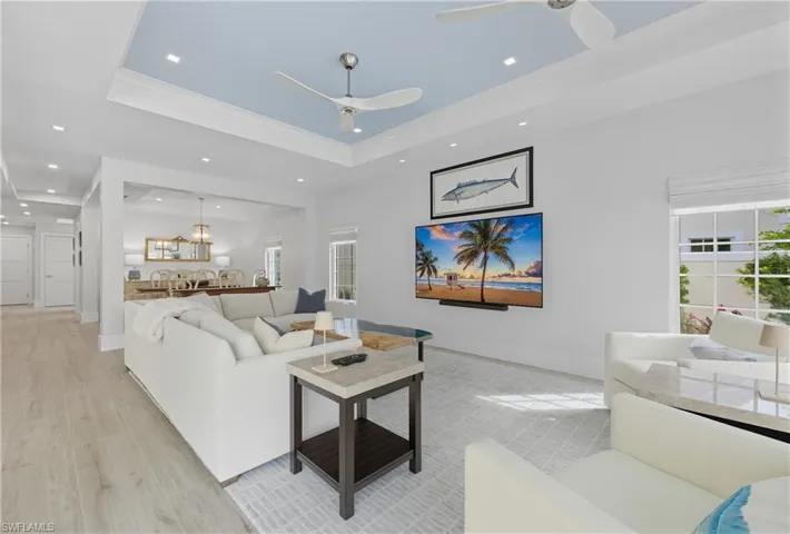 Living area featuring a raised ceiling, recessed lighting, and wood finished floors