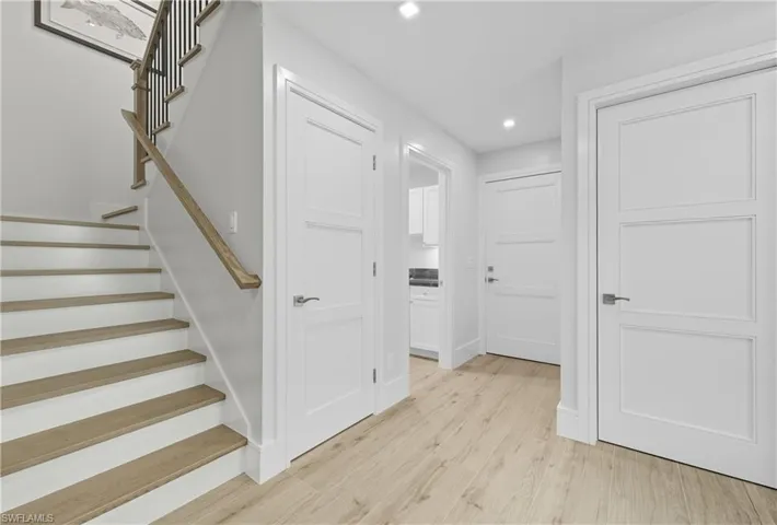 Hallway with stairway, light wood-type flooring, and recessed lighting