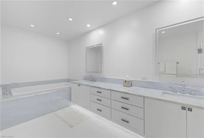 Bathroom with double vanity, a bath, and recessed lighting