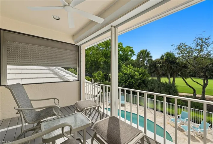 Balcony with view of pool and a ceiling fan