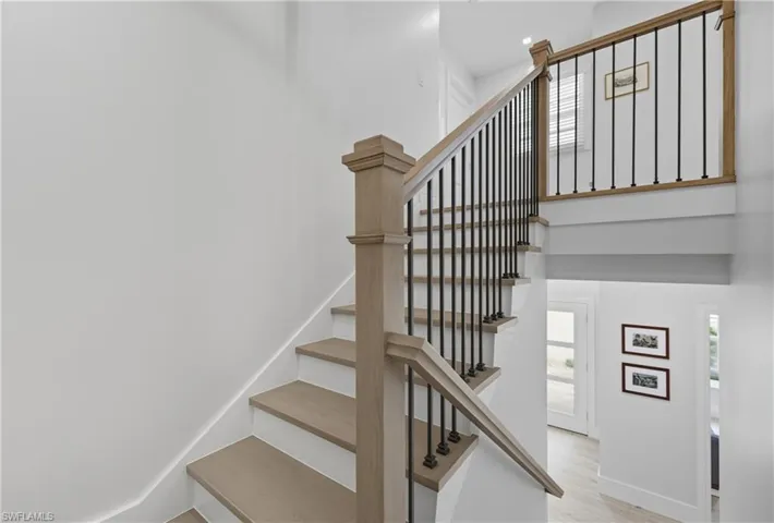 Stairway with wood finished floors and a towering ceiling