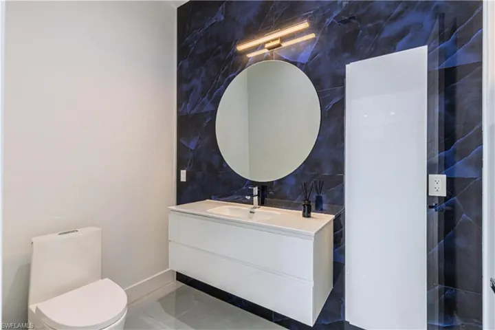 Bathroom featuring toilet, tile patterned floors, tile walls, and vanity