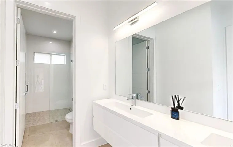 Bathroom with a sink, toilet, double vanity, tile patterned floors, and a stall shower