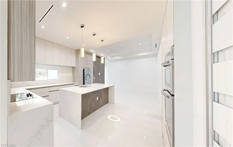 Kitchen with modern cabinets, a sink, hanging light fixtures, a center island with sink, and black electric cooktop