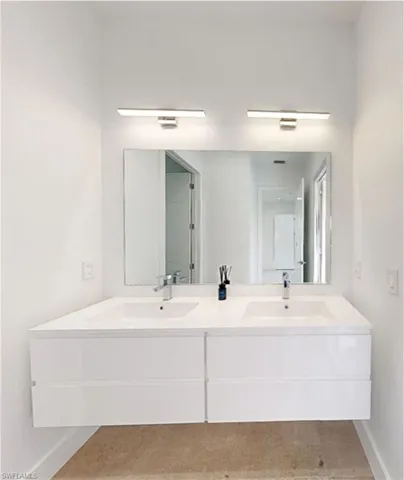 Bathroom featuring double vanity, baseboards, and a sink