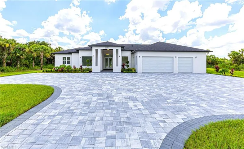 Prairie-style home featuring stucco siding, decorative driveway, a front lawn, french doors, and a garage