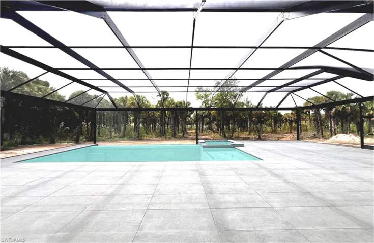 View of pool with a patio area, a pool with connected hot tub, and glass enclosure