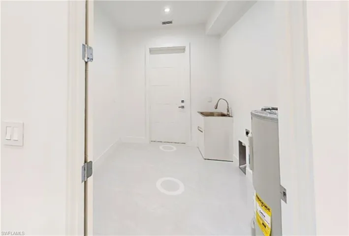 Washroom featuring laundry area, a sink, visible vents, and water heater