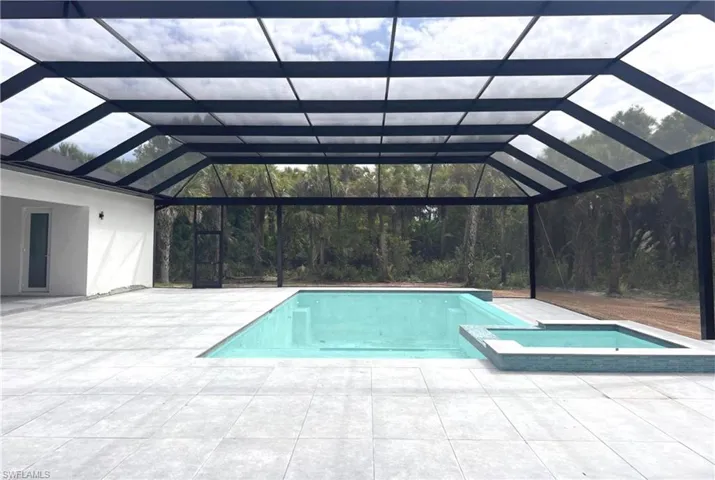 View of pool featuring a lanai, a patio, and a pool with connected hot tub