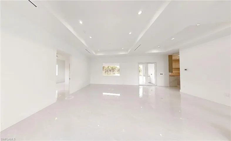 Spare room with recessed lighting, marble finish floor, and a tray ceiling